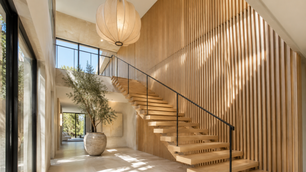 Modern staircase with a dramatic floor-to-ceiling white oak slatted feature wall.