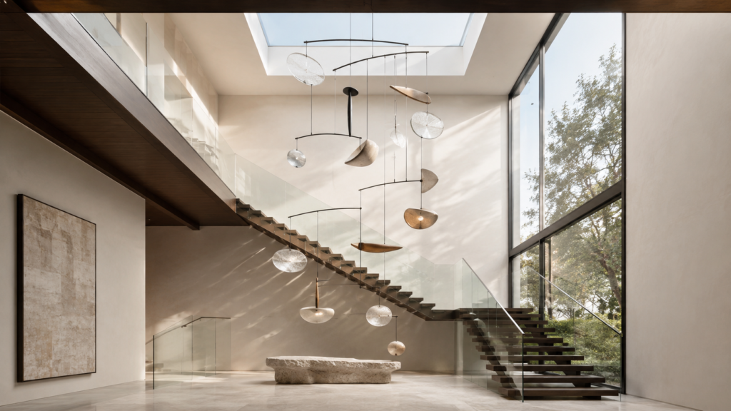 Oversized suspended sculptural mobile floating within a dramatic double-height staircase.