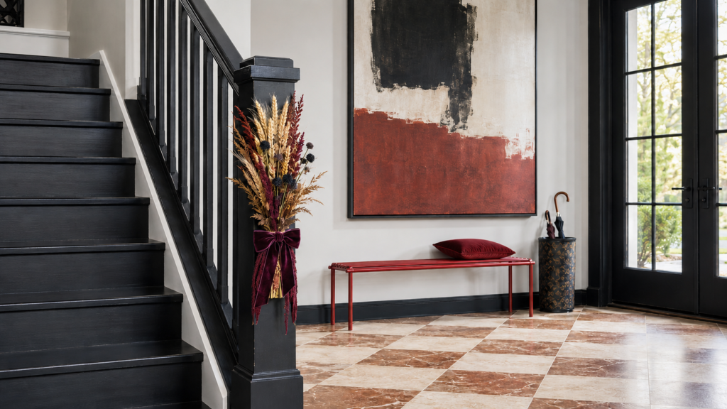 velvet-wheat-newel-post-arrangement.webp — Modern staircase newel post decorated with dried wheat, burgundy botanicals, and plum velvet ribbon