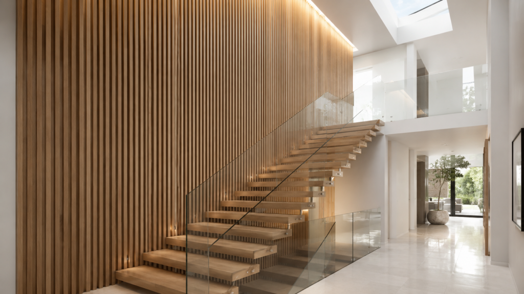 Full-height vertical white oak slat wall beside a floating modern staircase.