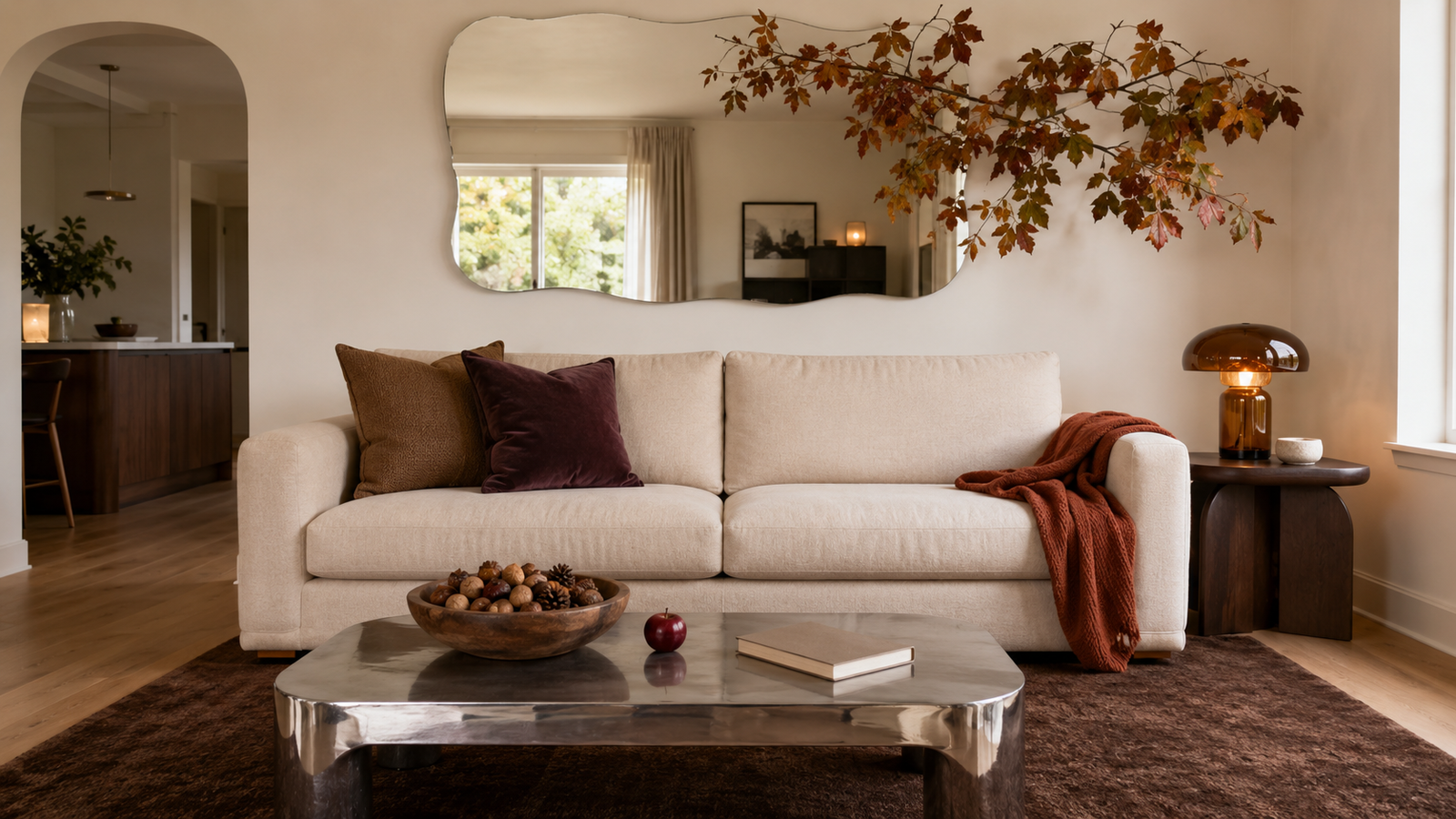 Modern organic living room decorated for fall with rust and plum textiles, autumn branches, warm wood, clay, and a chrome coffee table.