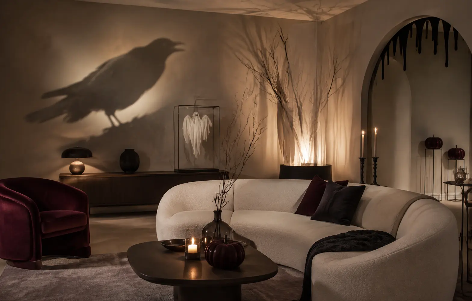 Elegant spooky-chic living room decorated for Halloween with burgundy accents, dark branches, candlelight, raven shadows, pumpkins, and sophisticated gothic decor.